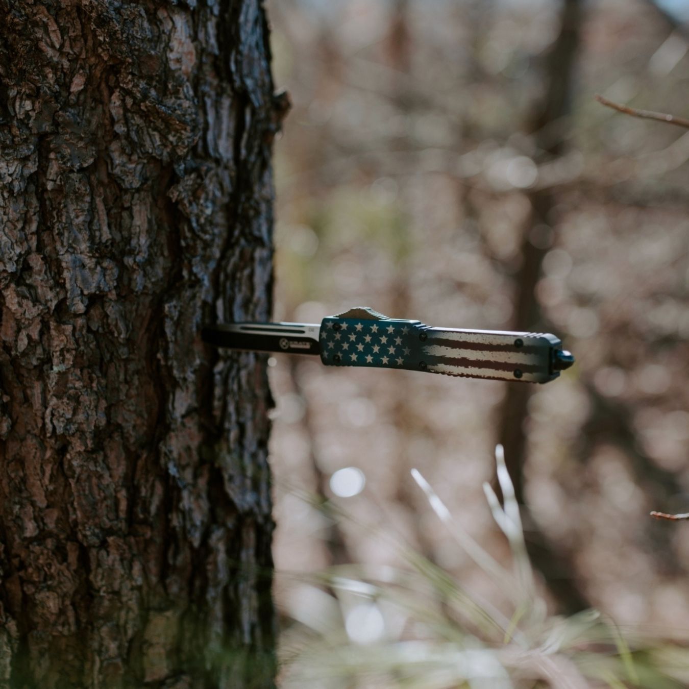 otf knife with blade stuck into a tree