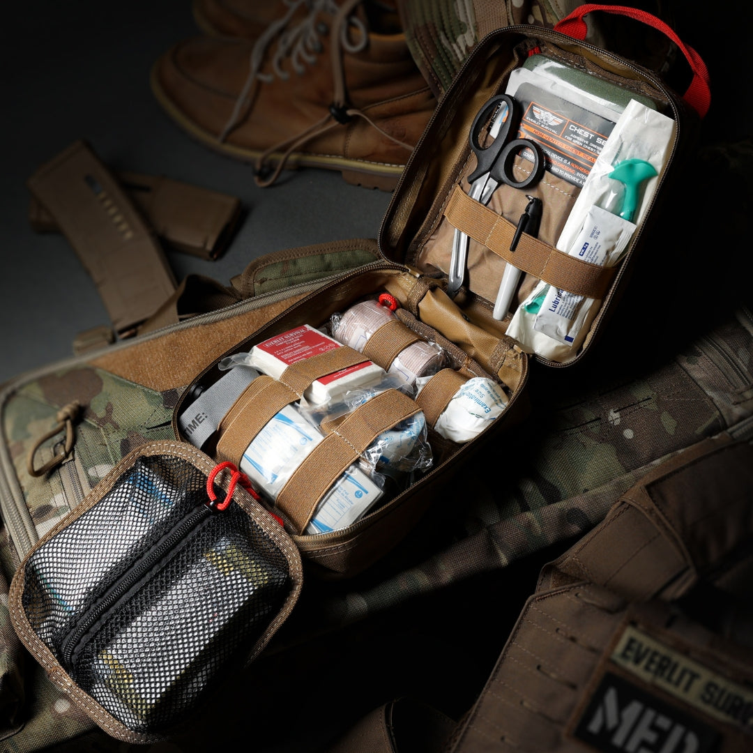 Open first aid kit with medical supplies on a camouflage surface