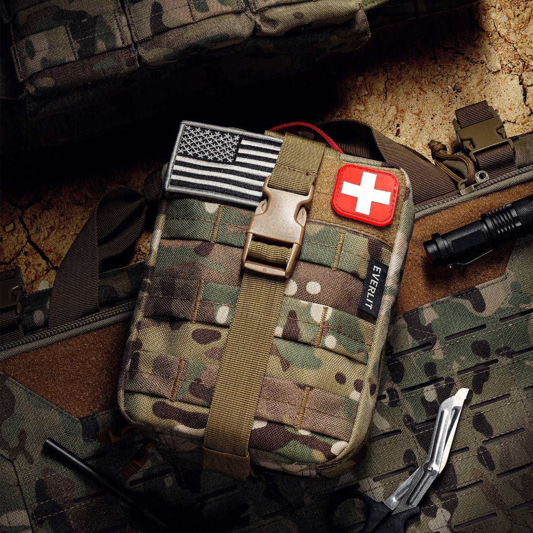 Camouflage trauma kit with American flag and medical cross patch on a camouflage background