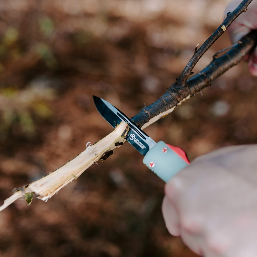 jade otf knife being used to shave a tree branch