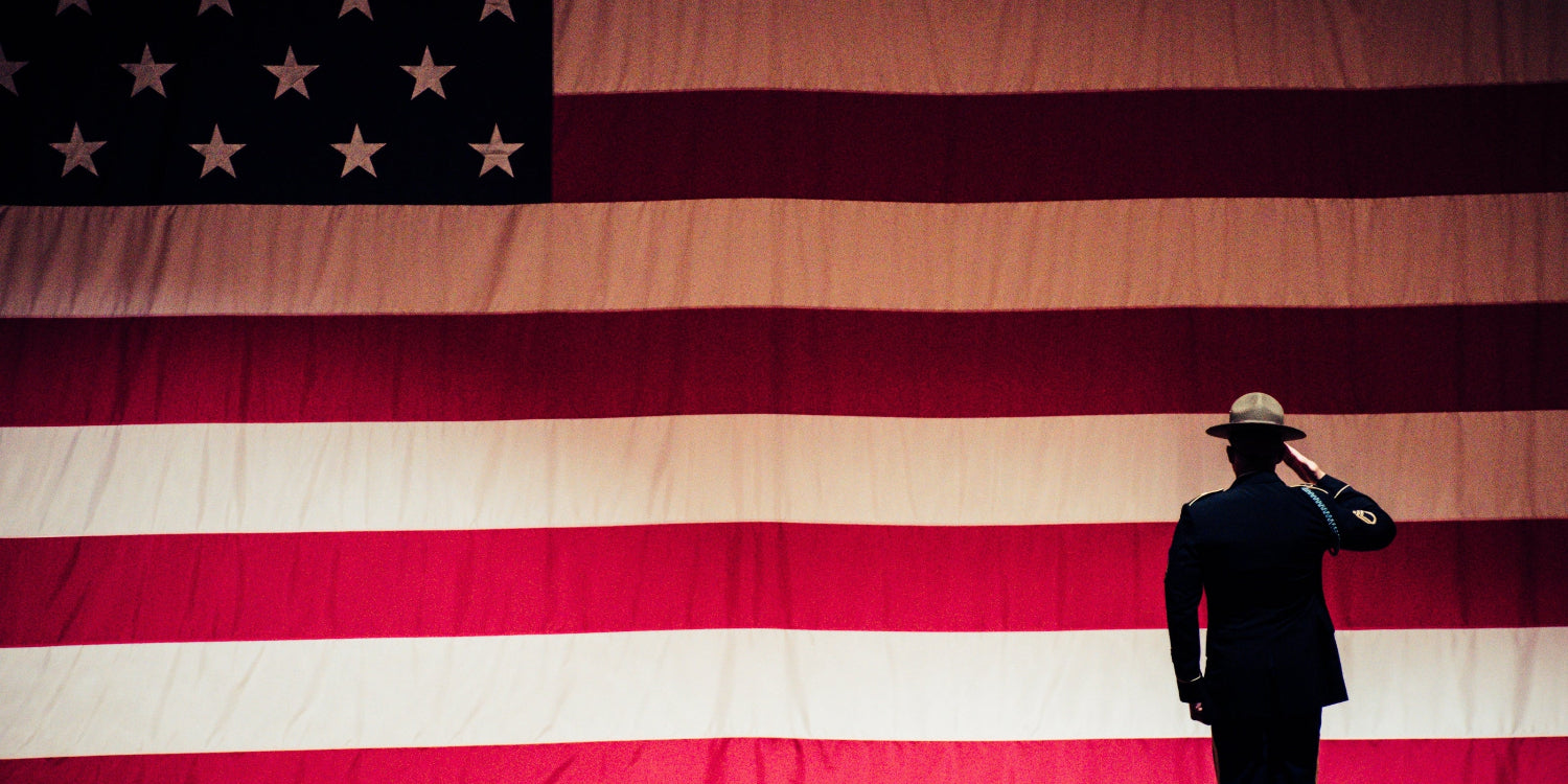 Person saluting in front of a large American flag
